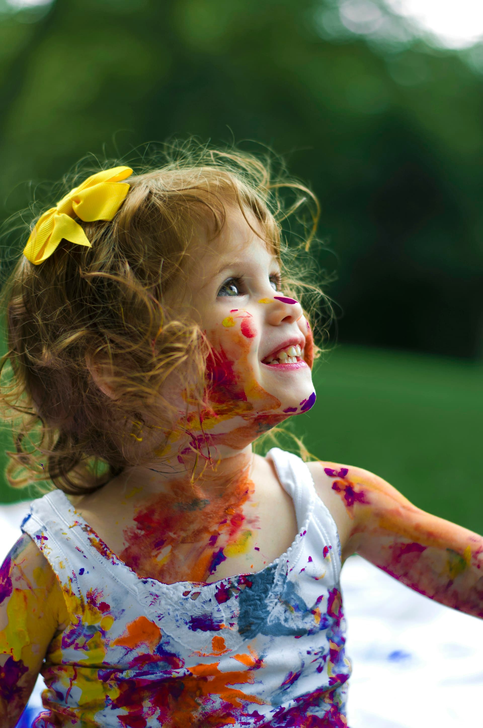 A smiling child covered in paint, looking up