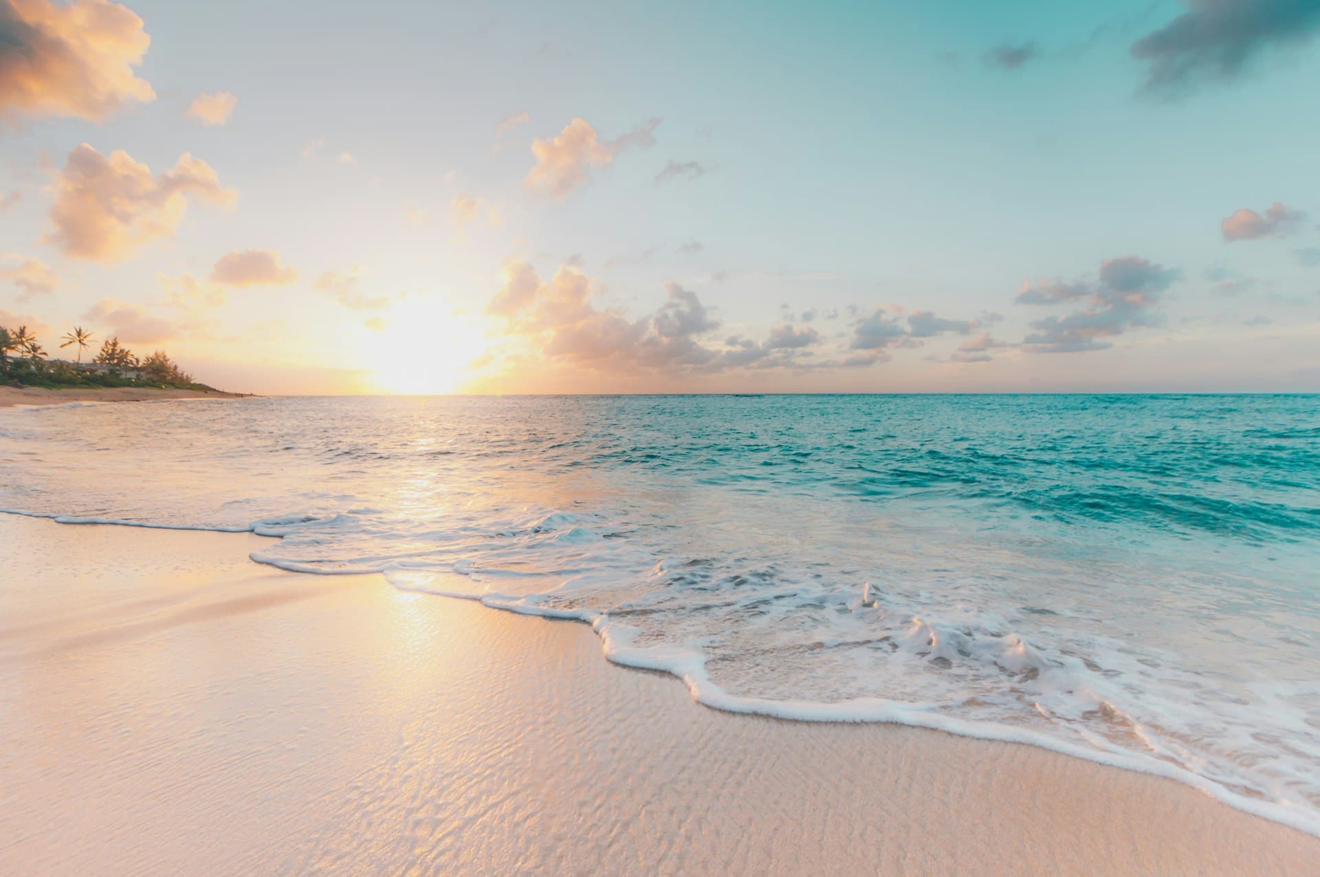 Waves washing onto a sandy beach at sunset